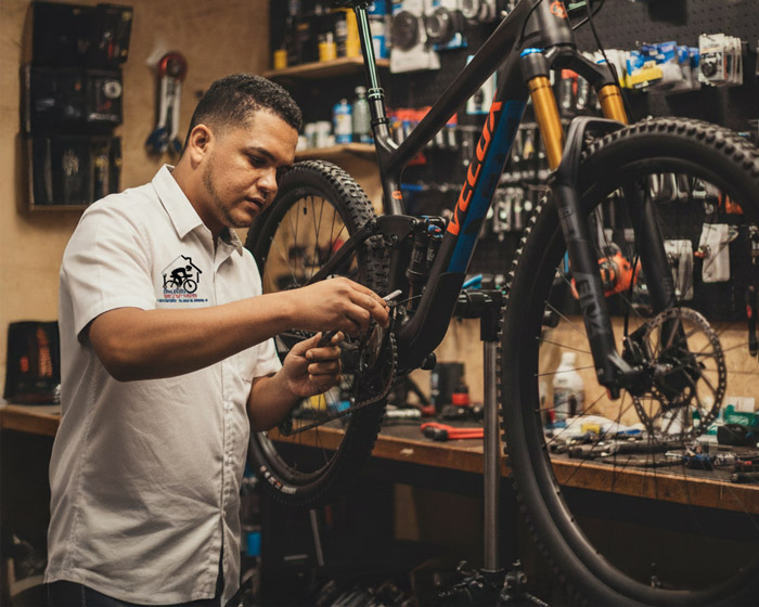 Retrato auténtico de Sterling Núñez trabajando en su taller de ciclismo